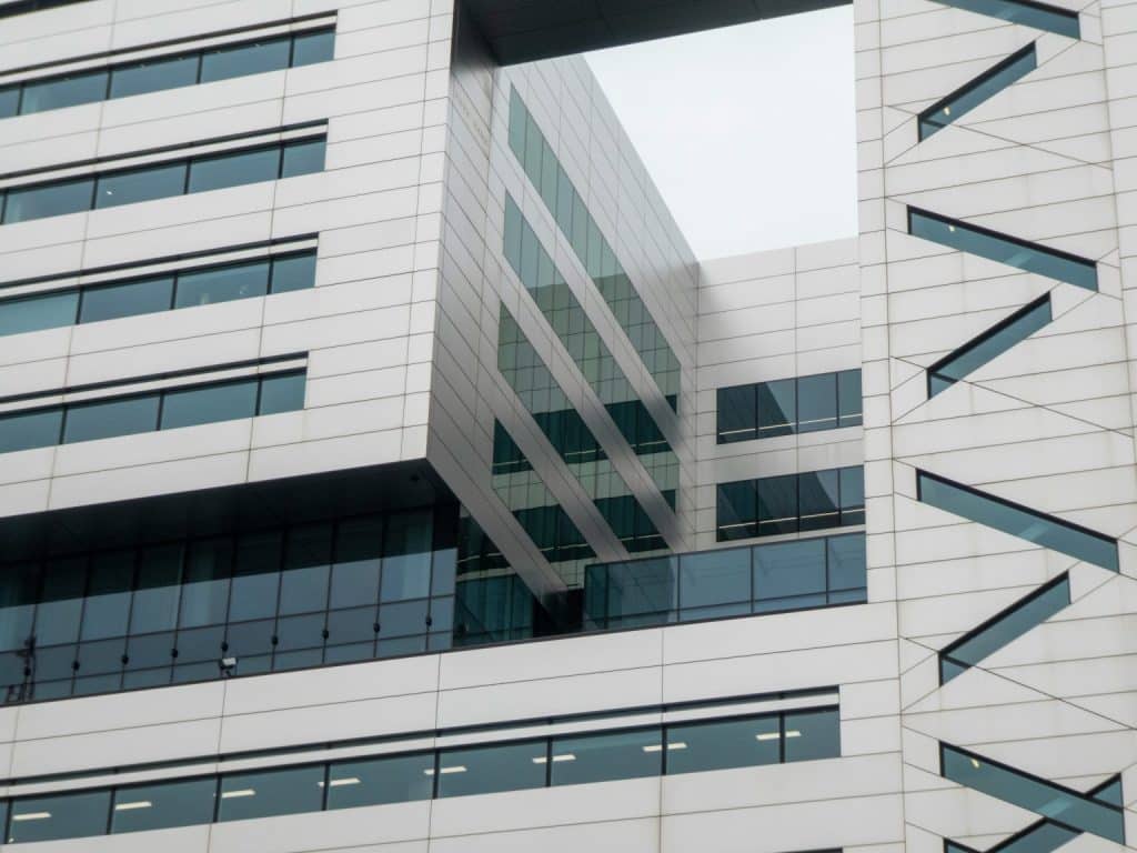 A modern building with a large rectangular cutout revealing another building behind it, all with many windows.