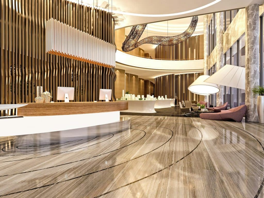 A luxurious, modern hotel lobby with a reception desk, large white lamps, and elegant marble floors.